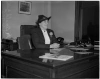 Mrs. Betty McDonald Miller wearing a hat while seated at a desk, Los Angeles