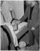 Unknown man holds Margaret Long's hand as she lays in a hospital bed, Los Angeles