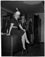 Gladys Jackson sits on a desk wearing a dress and hat, Los Angeles, 1930s