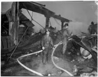 Firefighters walk through the ruins of a fire that occurred at Dura Steel Products Co., Los Angeles, 1940