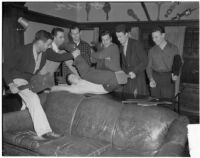 USC Kappa Alpha members spank another member with wooden paddles inside their fraternity house, Los Angeles, 1940