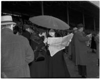 Two women under an umbrella on a rainy Derby Day at Santa Anita Park, Arcadia, February 22, 1940