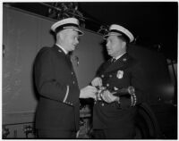 Deputy Fire Chief Herbert A. Krumsiek and Assistant Fire Chief W.H. Augustine holding a fire hose, Los Angeles, March 4, 1940