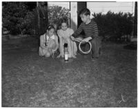 Sally Pact, Eleanor Green, and Stanley Feldman play on the grass at the Beverly Hills Athletic Club, Beverly Hills, March 2, 1940