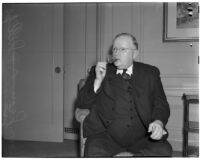 Oklahoma Governor Leon C. Phillips sitting in a chair and lighting a cigar, circa 1940