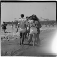 Group of teenage girls stand at the edge of the water at the beach on Labor Day, Los Angeles, September 3, 1945