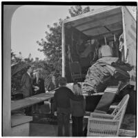 Louis M. Rich family watches as their possessions are loaded into a moving van, Los Angeles, November 22, 1945