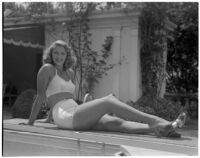 Actress Frances Staub poses poolside in a white bathing suit, Los Angeles, 1940s