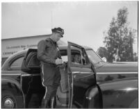 Police officer Dick Barlow writing a ticket for Dick Russell during a planned race to demonstrate the importance of following traffic laws, Los Angeles, 1947
