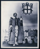 Laurence Olivier stands in costume before a miniature set in a publicity photograph for Henry V
