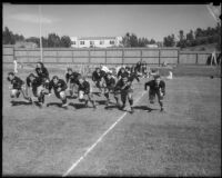 UCLA football team runs across Spaulding Field during practice, Los Angeles, 1930s