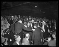 Policeman preventing a fight between wrestling fans, Los Angeles, 1936