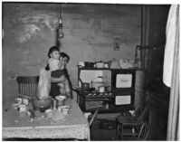 Poverty-stricken woman and child pictured inside a kitchen, Los Angeles, 1930s