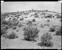 Unidentified desert area with two men on top of hill, California