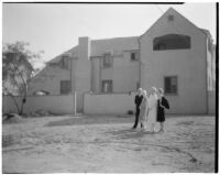 Laura La Plante residence, back view of house with Laura La Plante, 2 women and 1 man standing on unfinished grounds, Beverly Hills, 1926