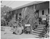 Avila Adobe, front view of porch, steps, and man with cart, Olvera Street, Los Angeles, 1934