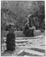Avila Adobe, view of patio with fountain and seated woman with watering can, Olvera Street, Los Angeles, 1934