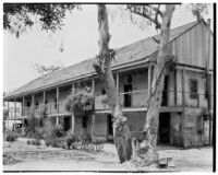 Rancho Los Cerritos, side view from east of decaying house, balcony, walkway, and car, Long Beach, 1930