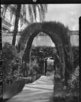 Gardens at Alcázar of Seville, view of two cypress arches over a walkway, Seville, Spain, 1929