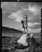 Rosita Dee Cornell standing on a rock in Pigeon Pass, shielding her eyes from the sun, Riverside, 1936