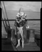 Ruth Iva Cornell standing on the deck of a ship wearing a stack of leis, Hawaii, 1938