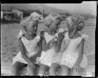 Mawby triplets seated on bench at the beach, Malibu, 1928