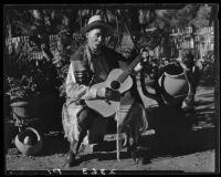 Eugene R. Plummer with guitar and Indian artifacts, West Hollywood, 1927