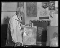 Henry William Cannon in studio with paintings on wall and on table, Los Angeles, 1927