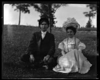 Man and woman in formal dress seated on lawn