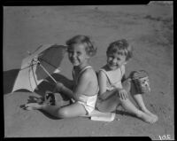 Children on sand with umbrella and pail, Los Angeles, circa 1935