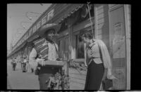 Street vendor and Jean Myras outside long storefront bar, Tijuana, 1931