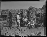 Three men in front of a small stone building in the desert, Palm Springs vicinity