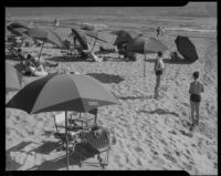 Beach with umbrellas and sunbathers, [1930s?]
