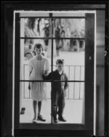 Children on porch looking through glass door, Los Angeles, circa 1935