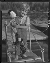 Boy on gangplank holding clown doll, Lake Arrowhead, 1929
