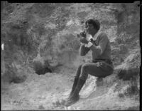 Clarice Barclay at rocky hillside powdering her face with natural silica, near Magic Mountain, Ventura County, 1930