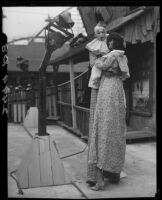 Clown on stilts dancing with tall puppet, advertising dance marathon, Santa Monica, 1928