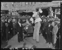 Clown on stilts, advertising dance marathon, with man in tuxedo, Santa Monica, 1928