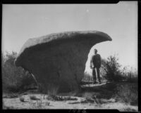 Henry Barnbrock under rock formation, Riverside County, [1920-1939?]