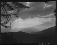 Mountains, pine trees, and sun through clouds, near Lake Arrowhead, 1929