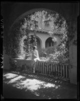 Woman on fence under arch, Virginia Hotel, Long Beach, 1929