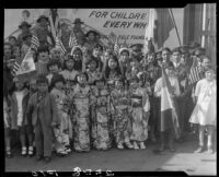 Children in ethnic dress posing with billboard advertising Golden Rule Week at Golden Rule Foundation Pageant, Los Angeles, 1930