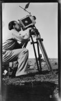 Paul Rotha seated and looking through a Parvo motion picture camera during the filming of Contact, Capernaum, 1932