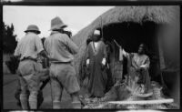 Filmmaker Paul Rotha and cameraman Horace Wheddon filming a tribal chief seated at the entrance of his dwelling, Uganda, 1933