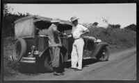 Cameraman Horace Wheddon pouring a drink next to a touring car, Nairobi, 1932