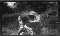 Filmmaker Paul Rotha filming near the Victoria Nile River, assisted by a Ugandan worker, Uganda, 1933
