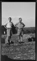 Filmmaker Paul Rotha and guide Captain Drysdale on a brick wall, Uganda, 1933
