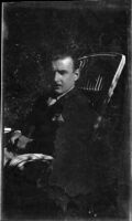 Filmmaker Paul Rotha seated on chair outdoors, Aswān, Egypt, 1933