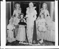 Peggy Hamilton modeling a Max Rée gown as "Queen Olympia" with members of her court at the Biltmore Hotel, Los Angeles, 1931