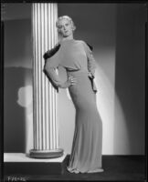 Peggy Hamilton modeling a full length dress with dolman sleeves and fur epaulettes, 1933